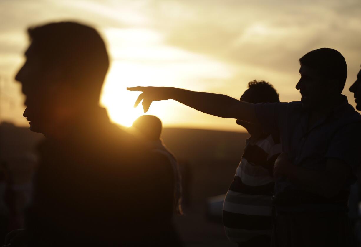 Turkish Kurds watch as airstrikes hit Kobani, inside Syria, as fighting intensifies between Syrian Kurds and the militants of Islamic State group, in Mursitpinar, on the outskirts of Suruc, at the Turkey-Syria border Wednesday.