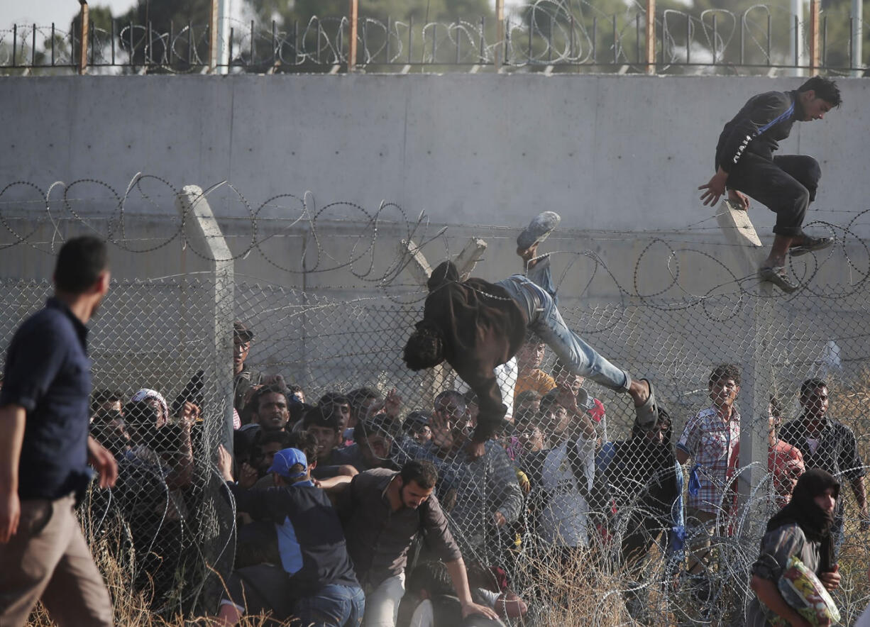 Syrian refugees cross into Turkey from Syria over and through a hole on the border fence Sunday in Akcakale, Sanliurfa province, Turkey. Thousands of Syrians cut through a border fence and crossed over into Turkey on Sunday, fleeing intense fighting in northern Syria between Kurdish fighters and jihadis.