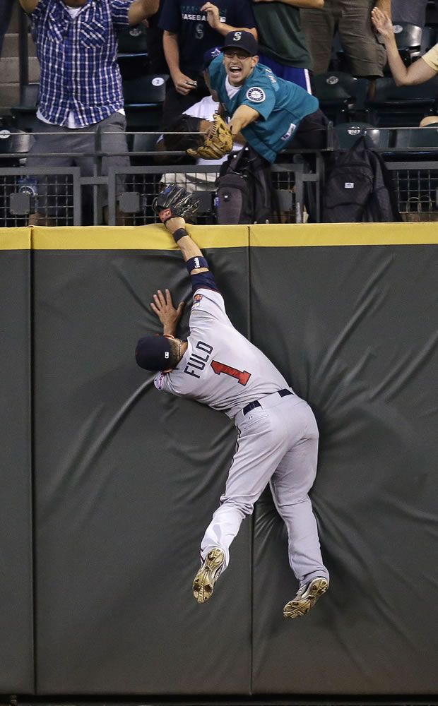 Minnesota Twins center fielder Sam Fuld slams into the outfield wall while chasing a deep fly ball from Seattle Mariners' Michael Saunders in the seventh inning Monday.