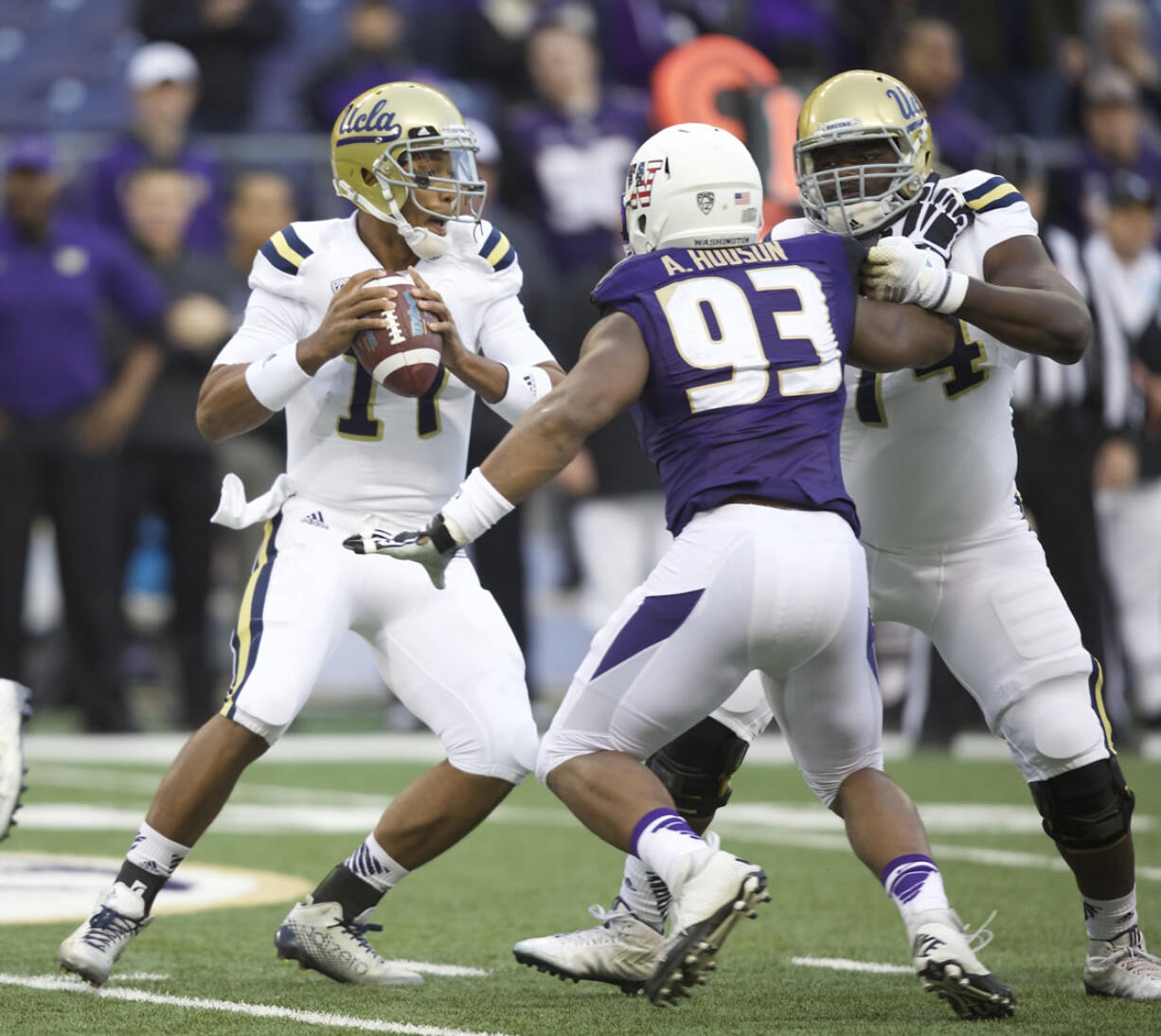 UCLA quarterback Brett Hundley, left, looks to pass as he avoids the rush of Washington defensive lineman Andrew Hudson in the first half Saturday, Nov. 8, 2014, in Seattle.