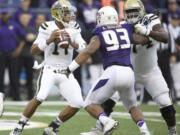 UCLA quarterback Brett Hundley, left, looks to pass as he avoids the rush of Washington defensive lineman Andrew Hudson in the first half Saturday, Nov. 8, 2014, in Seattle.