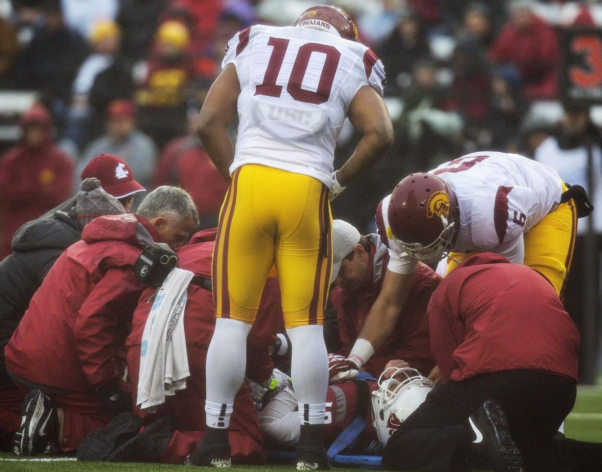 Southern California team captains linebacker Hayes Pullard (10) and quarterback Cody Kessler (6) check on injured Washington State quarterback Connor Halliday (12) during the first quarter Saturday, Nov. 1, 2014, at Martin Stadium in Pullman. Halliday was taken off the field and transported to at Pullman Regional Hospital in Pullman with a splint on his right leg.