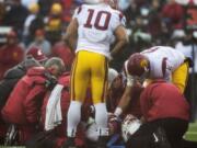 Southern California team captains linebacker Hayes Pullard (10) and quarterback Cody Kessler (6) check on injured Washington State quarterback Connor Halliday (12) during the first quarter Saturday, Nov. 1, 2014, at Martin Stadium in Pullman. Halliday was taken off the field and transported to at Pullman Regional Hospital in Pullman with a splint on his right leg.