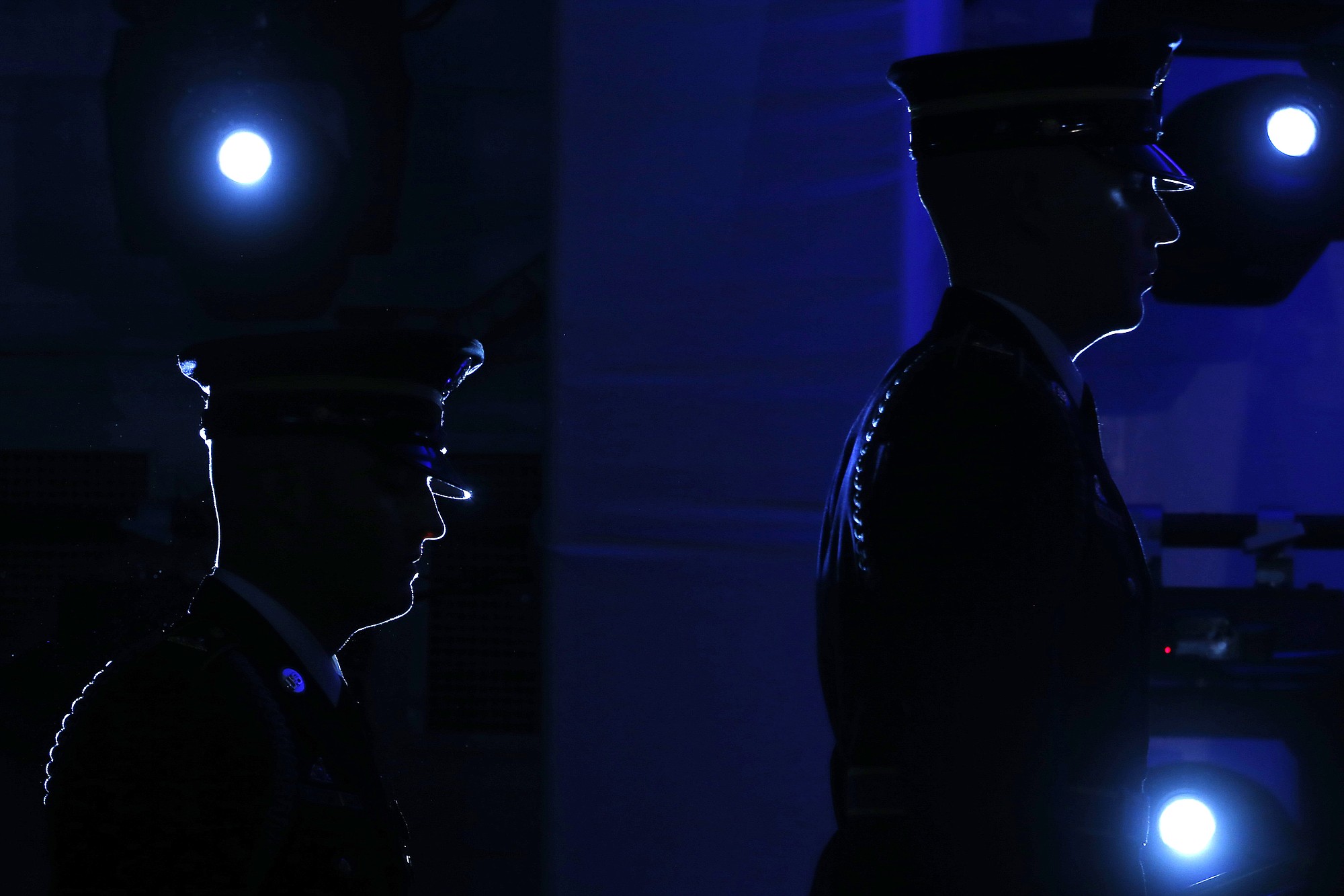 Military honor guard are illuminated by stage lights as they return to retrieve flags on stage at the end of the ceremony for the 20th anniversary of the United States Holocaust Memorial Museum in Washington on Monday