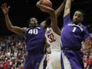 Washington State's Que Johnson (32) drives under the defense Washington's Shawn Kemp Jr. (40) and Darin Johnson during the first half Sunday, Feb. 22, 2015, in Pullman.