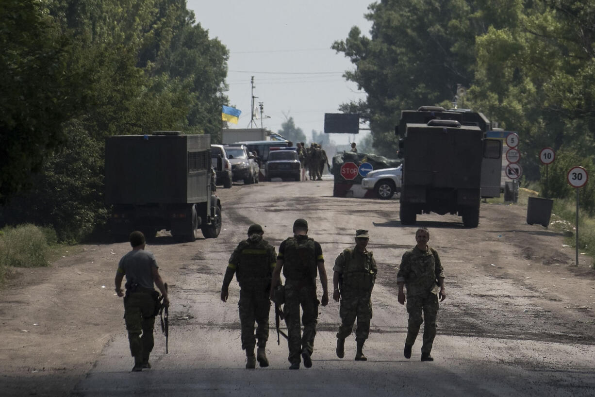 Ukrainian servicemen walk outside a checkpoint Thursday near Marinka, in the Donetsk region of Ukraine.