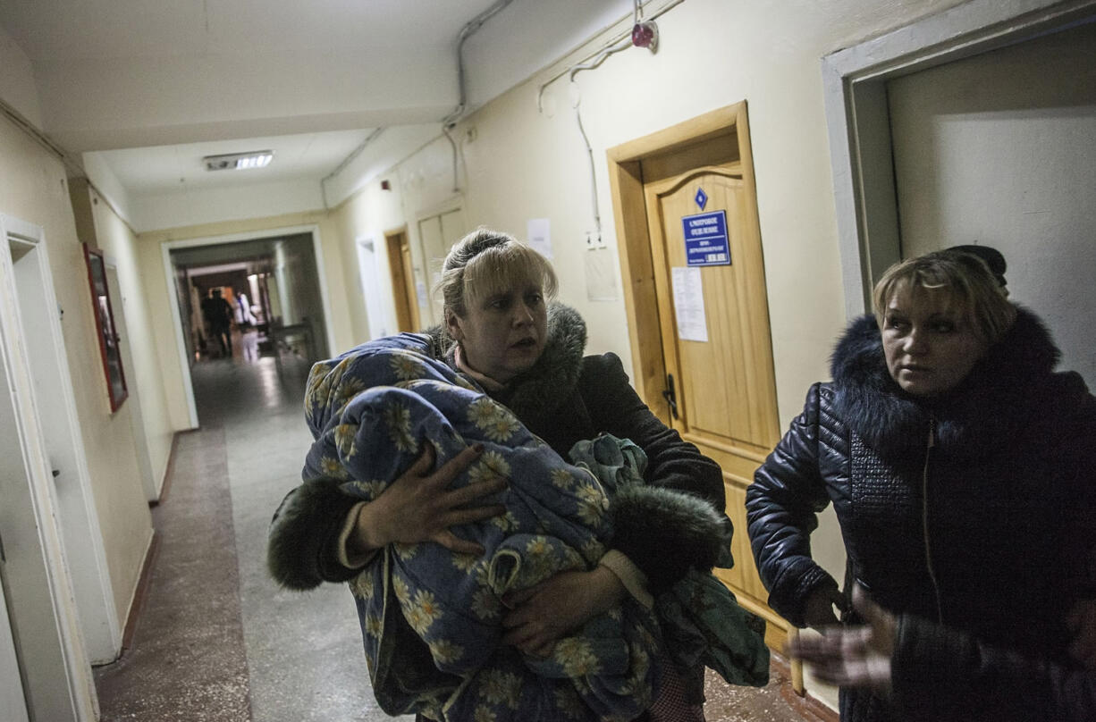 A woman holds a child Monday in the basement of Central Clinical Hospital No.