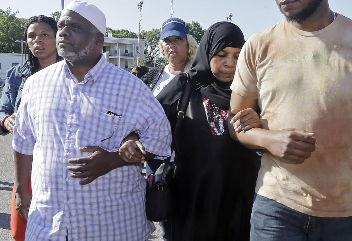 Rahimah Rahim, second from right, and Ibrahim Rahim, left, the mother and brother of shooting victim Usaama Rahim, walk away after a news conference on Thursday in Boston's Roslindale neighborhood in the area where he was shot to death.