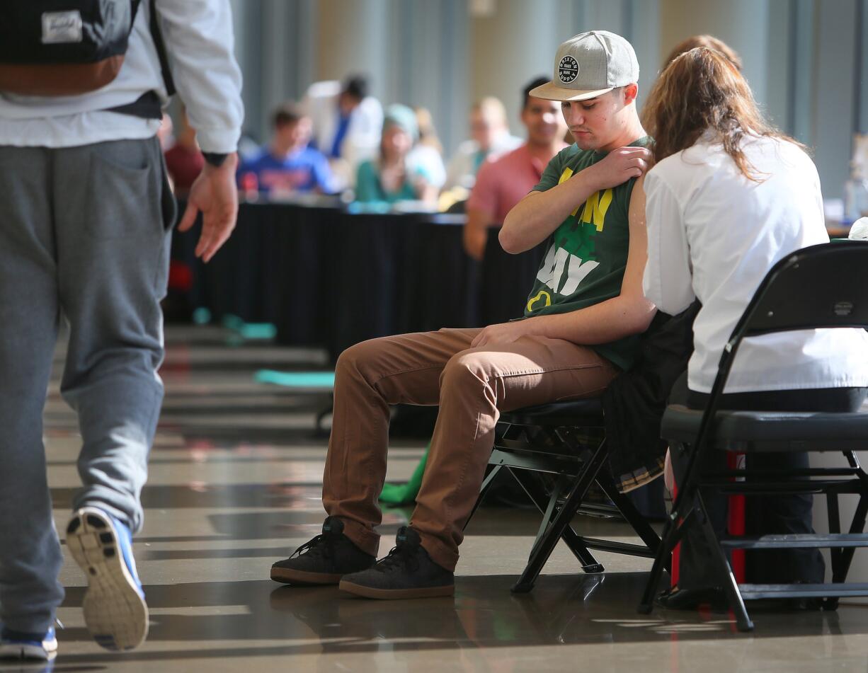 University of Oregon freshman Nick Dalzell, 19, is inoculated with a Meningitis B vaccine during a mass vaccination clinic at Matthew Knight Arena in Eugene, Ore., on Monday.