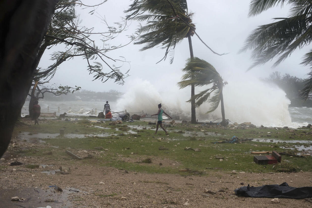 In this image provided by UNICEF Pacific people walk along the shore Saturday where debris is scattered in Port Vila, Vanuatu, in the aftermath of Cyclone Pam.