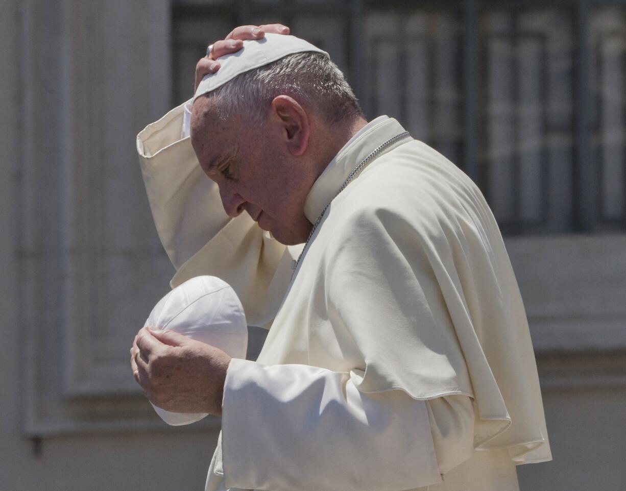 Pope Francis exchanges his skull cap with one donated to him as he leaves at the end of his weekly general audience in St.