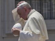 Pope Francis exchanges his skull cap with one donated to him as he leaves at the end of his weekly general audience in St.