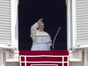 Pope Francis waves to the faithful as he arrives to recite the Angelus noon prayer from his studio window overlooking St.