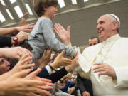 L'Osservatore Romano
Pope Francis greets a child Thursday at an audience with members of Pauline family in the Paul VI hall at the Vatican. The pope will be in the U.S. in September.