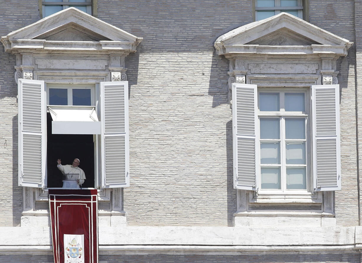 Pope Francis blesses the faithful as he celebrates the Angelus noon prayer from the window of his studio overlooking St.