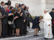 Pope Francis is greeted Friday by lay members as he arrives for an afternoon session of a two-week synod on family issues, at the Vatican. Gay rights groups are cautiously cheering a shift in tone from the Catholic Church toward homosexuals, encouraged that Pope Francis' famous &quot;Who am I to judge?&quot; position has filtered down to bishops debating family issues at a Vatican meeting this week.