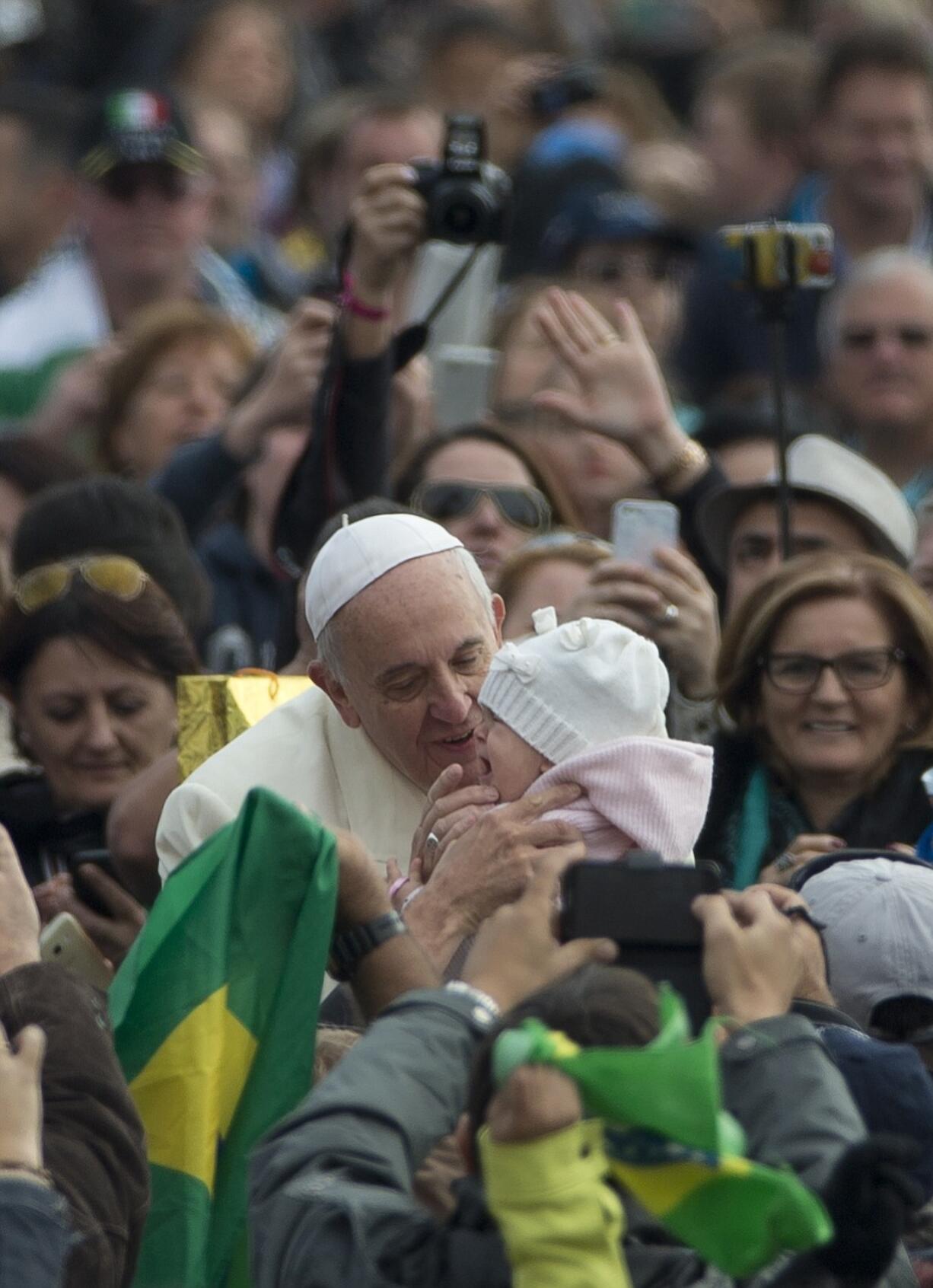 Pope Francis kisses a baby as he arrives for his weekly general audience in October in St.