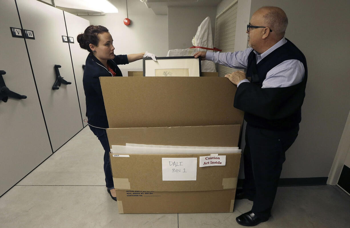 In this May 1, 2015 photo, Michael Labrie, director of collections and exhibitions at the Walt Disney Family Museum, right, and assistant registrar Jamie O'Keefe look through a bin of Salvador Dali art in a collections room at the Disney museum in San Francisco. Besides his love of wholesome entertainment, Walt Disney also had an appreciation for the eccentric that led to a short-lived partnership and decades-long friendship with surrealistic artist Salvador Dali.