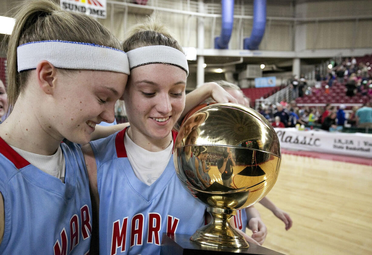 Mark Morris' Karley Eaton, right, and her twin sister, Kourtney Eaton, take the Class 2A girls championship basketball trophy off the court Saturday, March 7, 2015, at the Yakima Valley SunDome. Mark Morris defeated W.F. West 69-53.