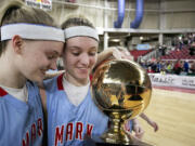 Mark Morris' Karley Eaton, right, and her twin sister, Kourtney Eaton, take the Class 2A girls championship basketball trophy off the court Saturday, March 7, 2015, at the Yakima Valley SunDome. Mark Morris defeated W.F. West 69-53.