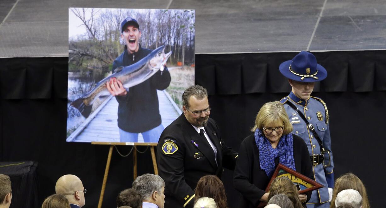 Trudi Inslee, wife of Gov. Jay Inslee, hands a state flag to the family of Richard Wheeler at a memorial service for three firefighters killed in a wildfire, Sunday, Aug. 30, 2015, in Wenatchee, Wash. Wheeler, Andrew Zajac and Thomas Zbyszewski died Aug. 19 in a fire near Twisp, Wash.