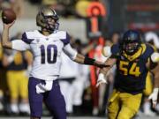 Washington quarterback Cyler Miles, left, passes under pressure from California's Austin Clark during the first half of an NCAA college football game Saturday, Oct. 11, 2014, in Berkeley, Calif.