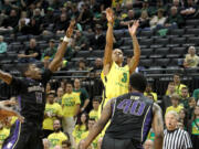 Oregon's Joseph Young, right, shoots a 3-point shot over Washington's Mike Anderson, left, and Shawn Kemp Jr., right, during the first half on Wednesday, Feb. 4, 2015.