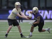 Washington quarterback Jake Browning, left, hands off to tailback Ralph Kinne, right, during spring football practice, Monday, March 30, 2015, in Seattle. (AP Photo/Ted S.