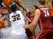 Washington State's Josh Hawkinson (24) and DaVonte Lacy (25) defend against Oregon State's Jamal Reid (32) during the first half in Corvallis, Ore., Thursday, Feb.