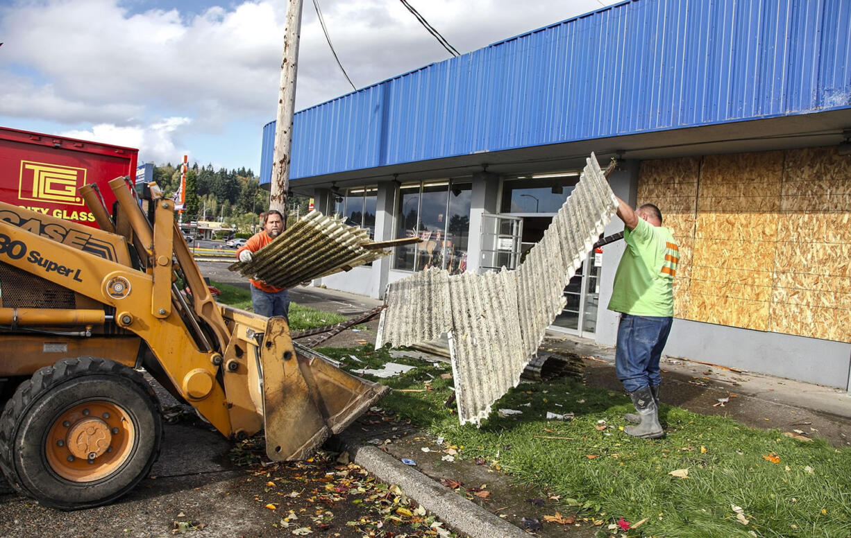 City of Longview workers, Mike Ward, left, and Rob Peters on Thursday dispose of the remaining portions of the Searing Electric and Plumbing roof which was ripped off a storage area and broke the windows, in Longview. A rare tornado ripped down power lines and damaged property Thursday in Longview, but there were no immediate reports of injuries, officials said.