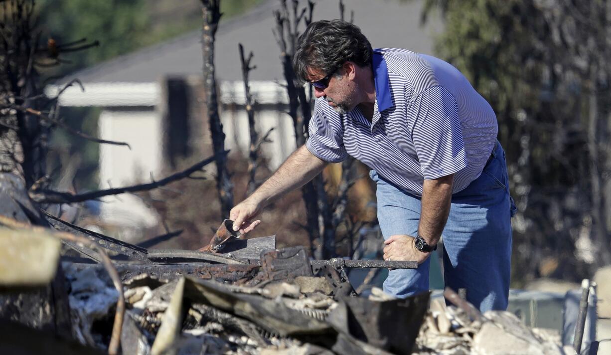 Vern Smith picks through the rubble of his home, destroyed in a wildfire the night before, Monday in Wenatchee.