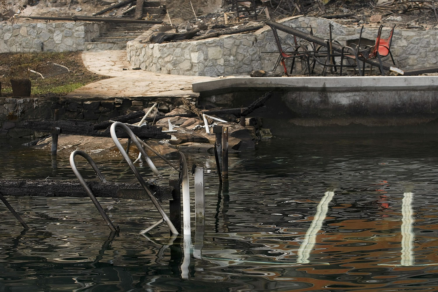 A burned dock and table set is seen at the site of a home that was destroyed in the First Creek wildfire days earlier on the west shoreline of Lake Chelan, Wash. on Sunday, Aug. 23, 2015.