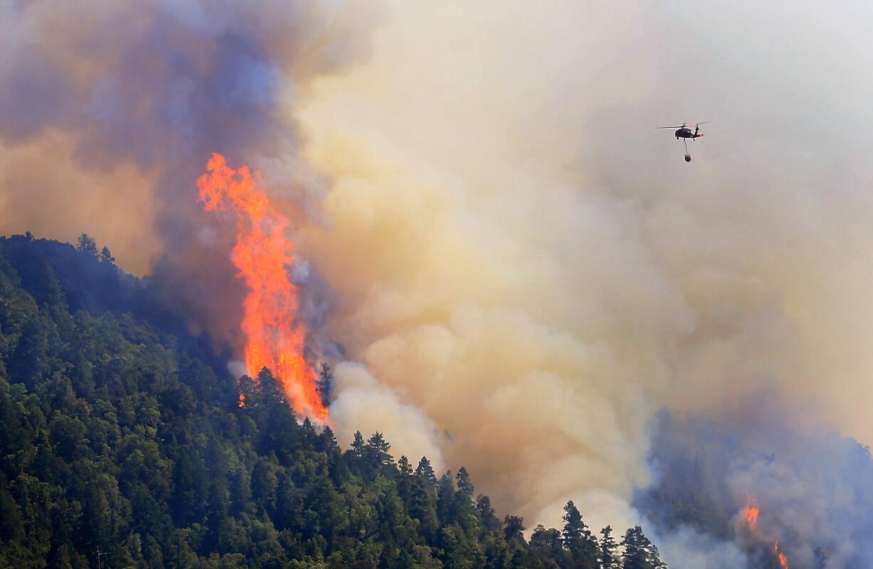 An Air National Guard helicopter moves in to make a water drop as the Lodge Fire Complex between Leggett and Laytonville, Calif., on  Friday.