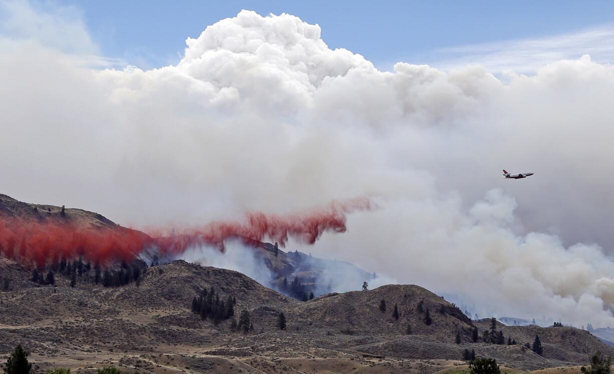 A DC-10 air tanker drops fire retardant over a wildfire as smoke rises and billows behind Saturday near Carlton.