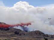 A DC-10 air tanker drops fire retardant over a wildfire as smoke rises and billows behind Saturday near Carlton.