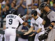 Seattle Mariners' Endy Chavez (9) is greeted at the plate by Mike Zunino, center, as Chicago White Sox catcher Tyler Flowers watches at right, after Chavez hit a two-run home run in the fourth inning of a baseball game, Thursday, Aug. 7, 2014, in Seattle. (AP Photo/Ted S.