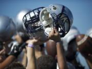 Heritage High School football players raise their helmets after a practice in 2012.