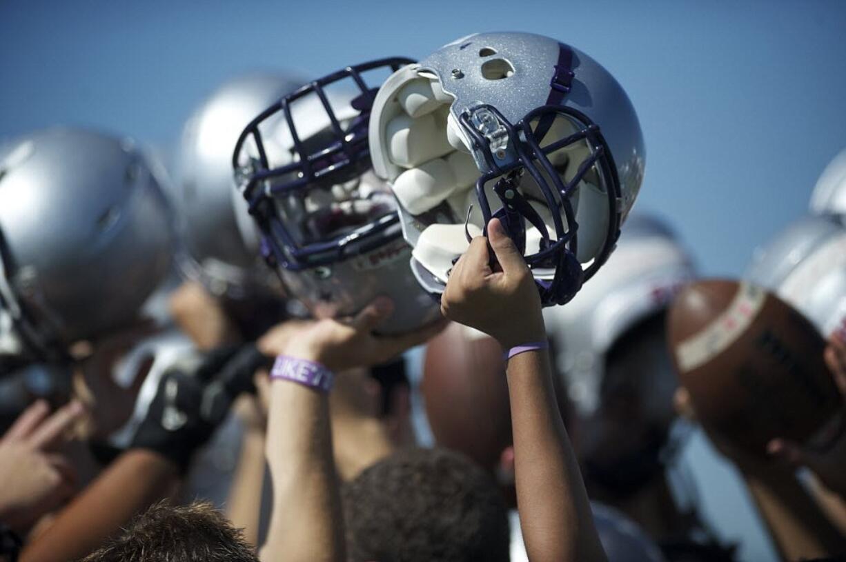 Heritage High School football players raise their helmets after a practice in 2012.