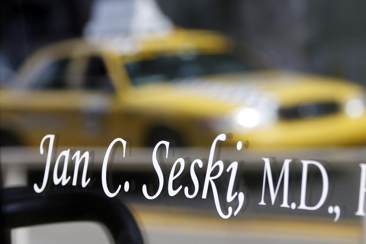 A taxi is reflected in the glass of the door on the the entrance to the office of Dr. Jan Casimir Seski on Sunday in Pittsburgh.