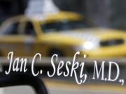 A taxi is reflected in the glass of the door on the the entrance to the office of Dr. Jan Casimir Seski on Sunday in Pittsburgh.