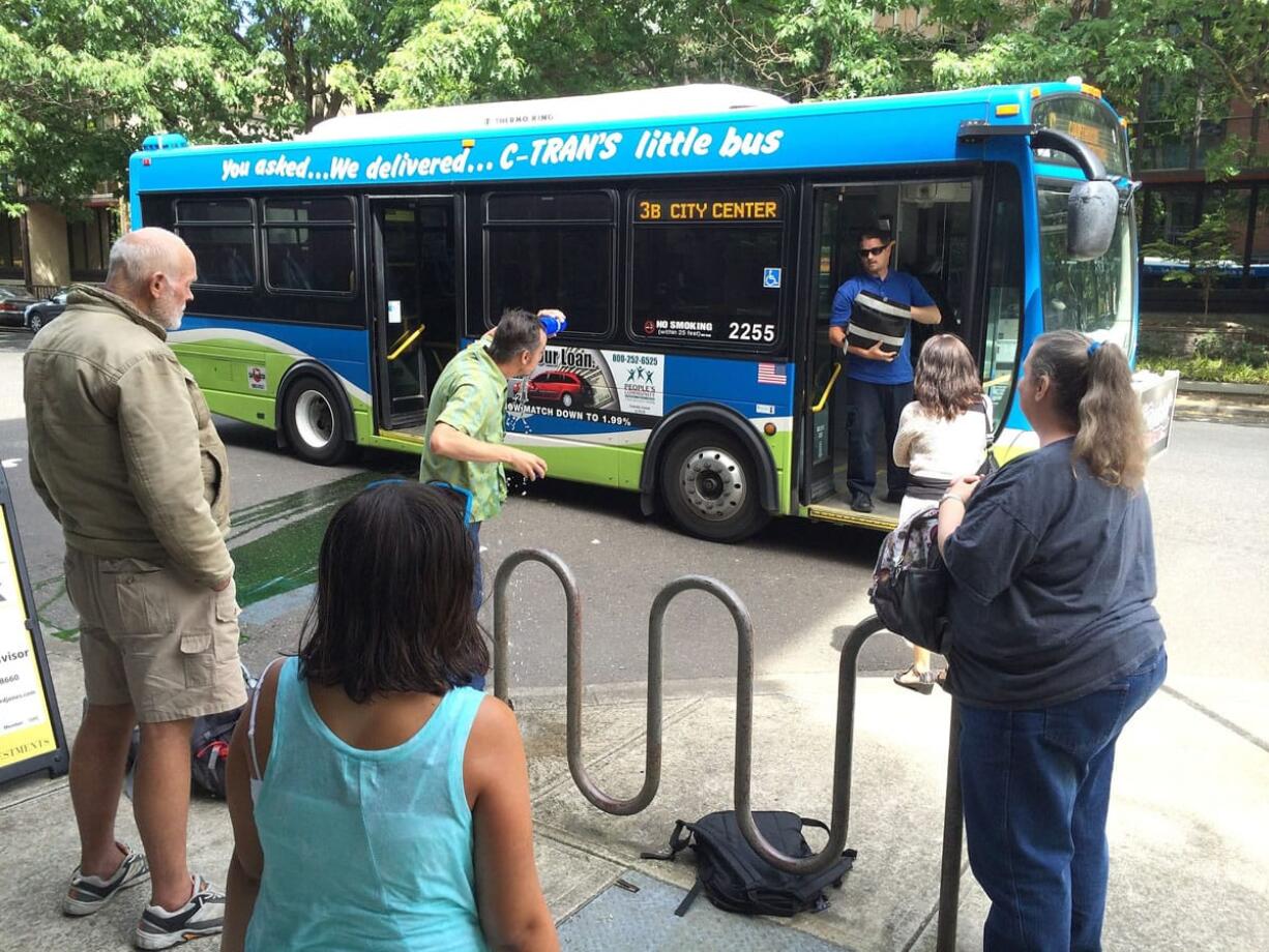 Kevin Taylor of Vancouver washes his eyes with water after fluid poured over him and his daughter, Dora (in foreground), as they were riding on a C-Tran bus Monday, July 21, 2014.