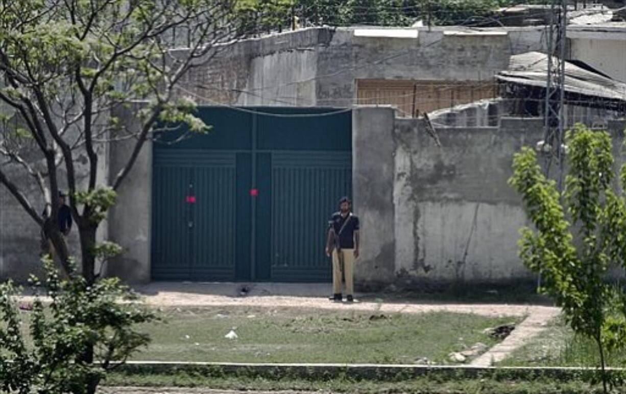 Pakistani police officers stand guard at the main gate of a house where al-Qaida leader Osama bin Laden was caught and killed in Abbottabad, Pakistan on Wednesday, May 4, 2011.