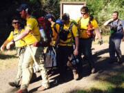 Emergency responders on Monday help carry a wounded dog to the trailhead on Dog Mountain.