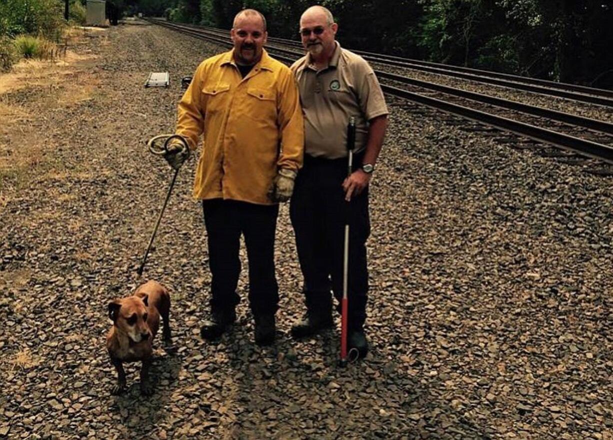 Firefighter Jeff Peterson, right, and animal control officer Bill Burrus pose for a photo with Penny, who they helped rescue from a patch of blackberries Sunday morning.