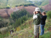 State wildlife biologists Eric Holman and Brooke George watch a herd of elk to see if the animals are limping.