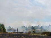 A field near the intersection of Padden Parkway and Andresen Road in Vancouver smolders after a fire Saturday.