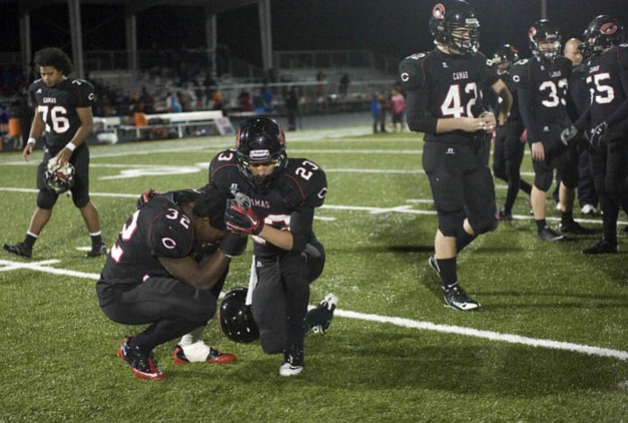 Camas High's Kamari Brown (32), center left, is consoled by teammate Vincente Huber (23) after an overtime loss to Lakes at Doc Harris Stadium in a 3A quarter final game on Friday November 19, 2010.