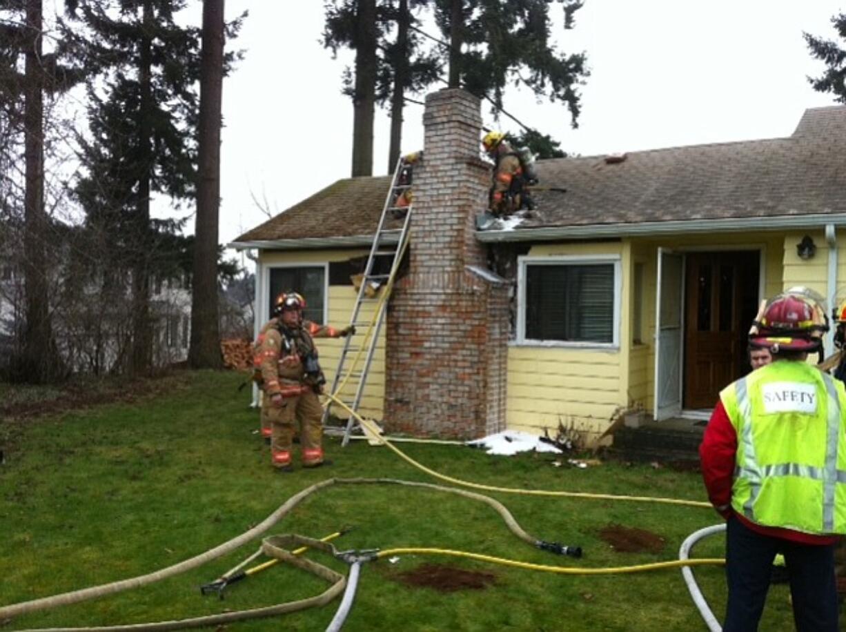 Firefighters examine the chimney area of a Sunnyside neighborhood home that caught fire this morning.