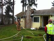 Firefighters examine the chimney area of a Sunnyside neighborhood home that caught fire this morning.