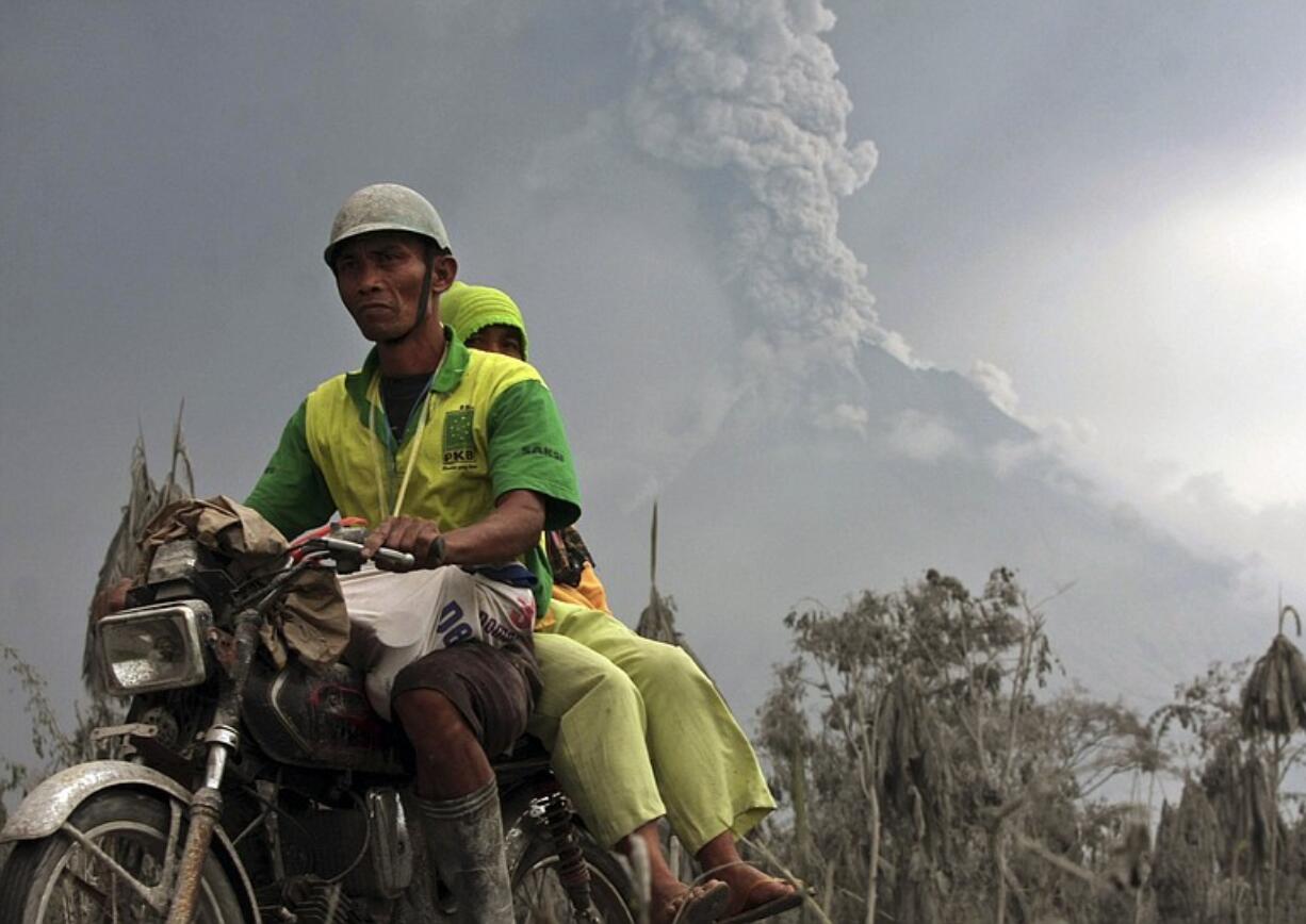 Villagers ride on a motorcycle as Mount Merapi continues to erupt.